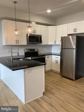 a kitchen with stainless steel appliances granite countertop a sink a stove a refrigerator and island with wooden floor