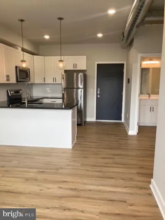 a kitchen with stainless steel appliances kitchen island granite countertop a refrigerator a stove and a wooden floor