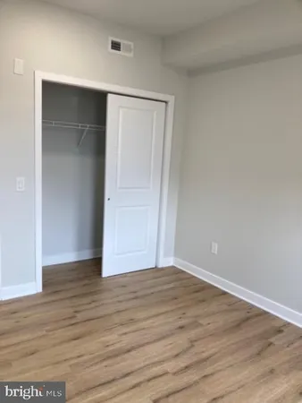 a view of an empty room with wooden floor and closet