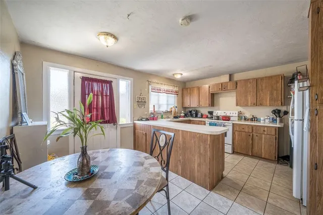 a kitchen with stainless steel appliances granite countertop a refrigerator a stove a sink dishwasher and a dining table with wooden floor