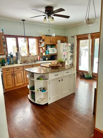 a kitchen with stainless steel appliances granite countertop a stove a sink dishwasher and a dining table with wooden floor