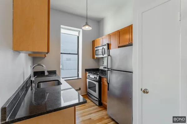 a kitchen with stainless steel appliances granite countertop a refrigerator a stove and a sink with wooden floor