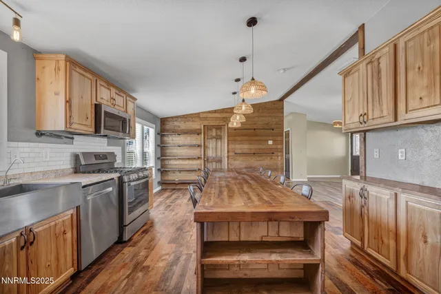 a room with stainless steel appliances kitchen island granite countertop a stove a refrigerator and a wooden cabinets