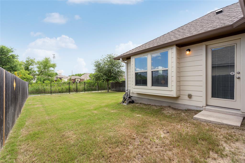 4719 Portillo Way Pflugerville, TX 78660 - Photo 27 of 27 Green grass fills a fenced backyard bordering the side of the home.