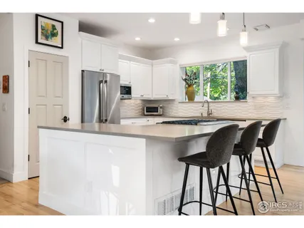 a kitchen with stainless steel appliances kitchen island a table chairs in it and wooden floors