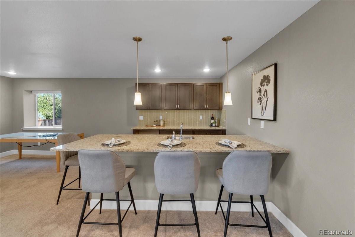 1721 Wingfeather Lane Castle Rock, CO 80108 - Photo 37 of 49 a kitchen with a dining table chairs and white cabinets