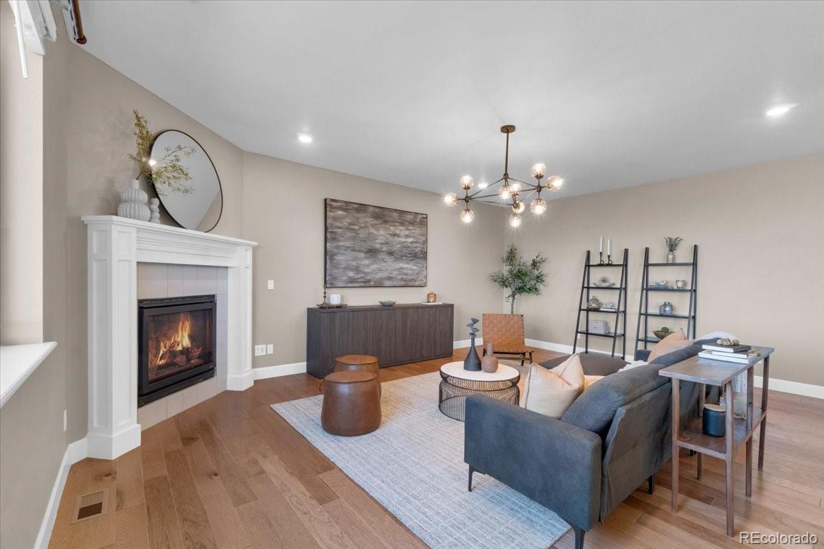 1721 Wingfeather Lane Castle Rock, CO 80108 - Photo 4 of 49 a living room with furniture a fireplace and a chandelier