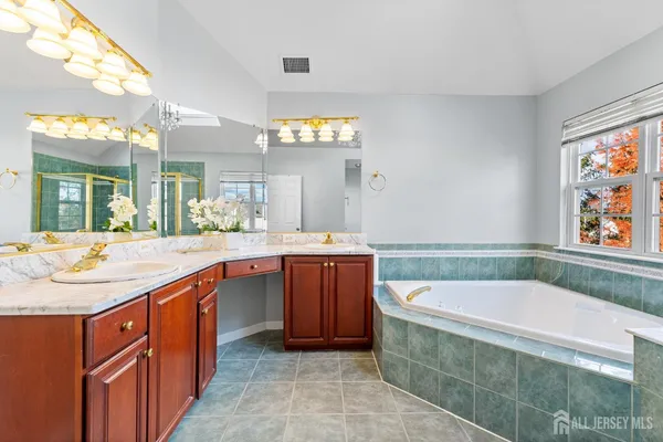 a bathroom with a granite countertop tub sink and mirror