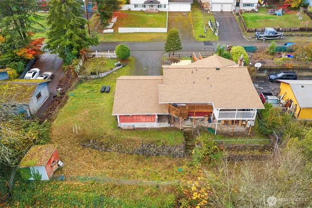 an aerial view of a house with swimming pool lawn chairs and large trees