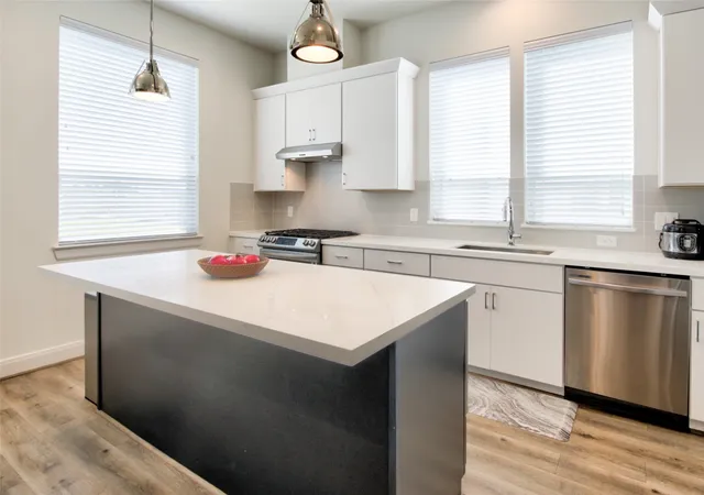 a kitchen with granite countertop a stove sink and refrigerator