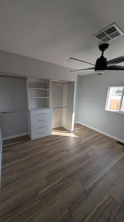 a view of empty room with wooden floor and fan