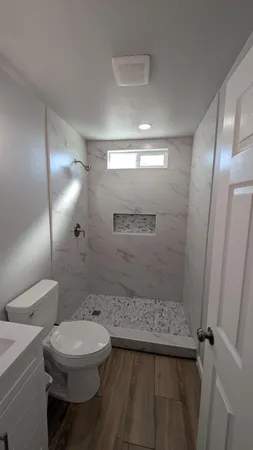 a bathroom with a sink a toilet a mirror and shower
