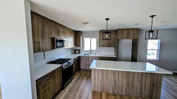 a kitchen with granite countertop a refrigerator a sink a stove and oven