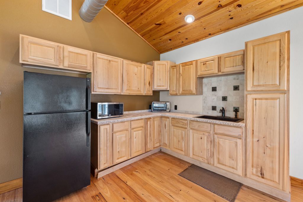 10800 Beach Road Leander, TX 78641 - Photo 26 of 39 A well-appointed kitchen features ample light wood cabinetry, natural wood flooring, and a convenient corner sink.