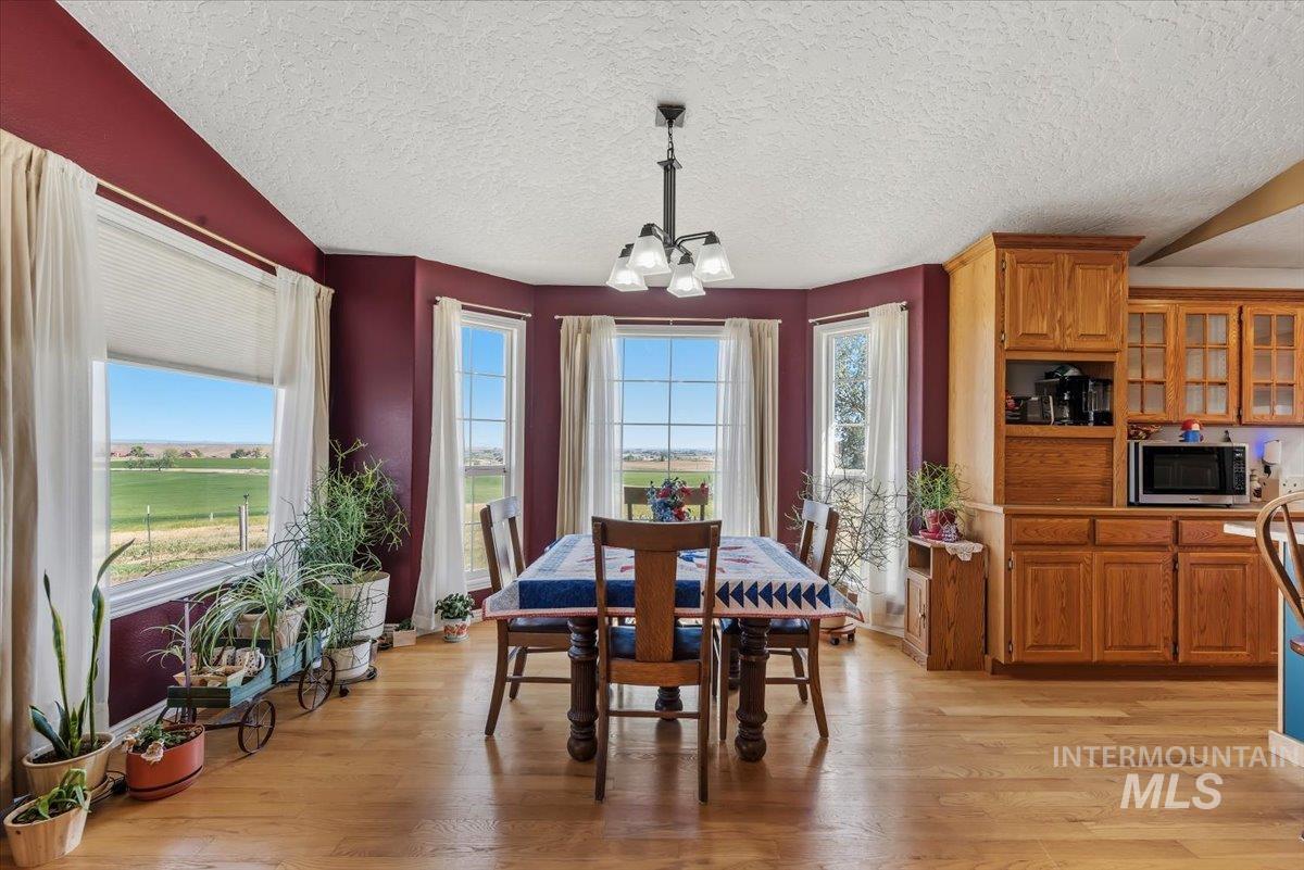 2331 Gulley Road Homedale, ID 83628 - Photo 10 of 46 Open concept space featuring a dining area with bay windows, wood-finish flooring, and an adjacent kitchen with wood cabinetry and built-in appliances