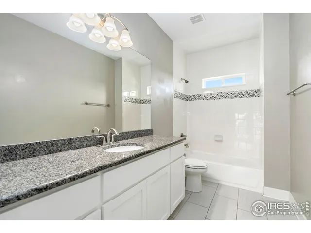 a bathroom with a granite countertop sink a toilet a mirror and shower