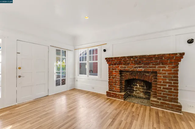 an empty room with wooden floor fireplace and windows