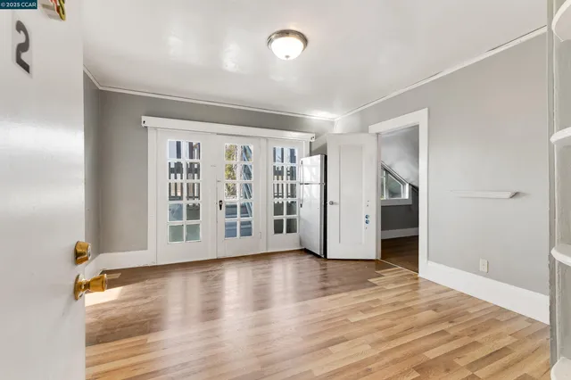 a view of an empty room with wooden floor and a window