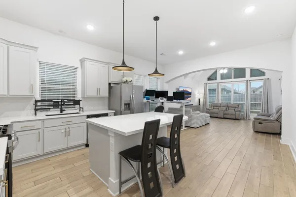 a kitchen with stainless steel appliances kitchen island granite countertop a stove a sink a dining table and chairs with wooden floor