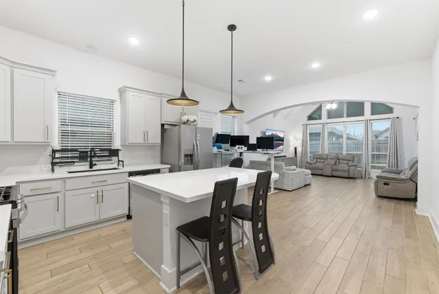 a kitchen with stainless steel appliances kitchen island granite countertop a stove a sink a dining table and chairs with wooden floor