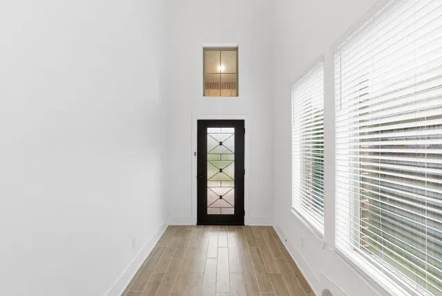a view of an empty room with window and wooden floor