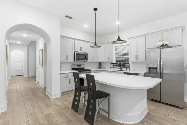 a kitchen with kitchen island a white counter top space a sink appliances and cabinets