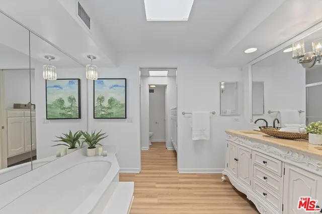a spacious bathroom with double vanity a mirror and a shower