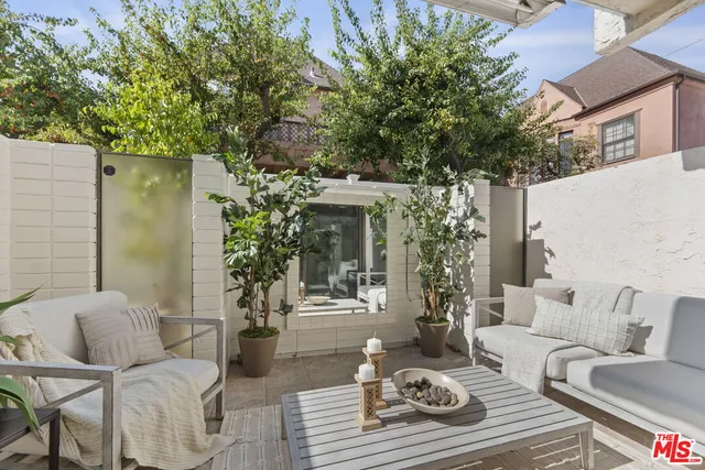a view of a patio with couches table and chairs and potted plants