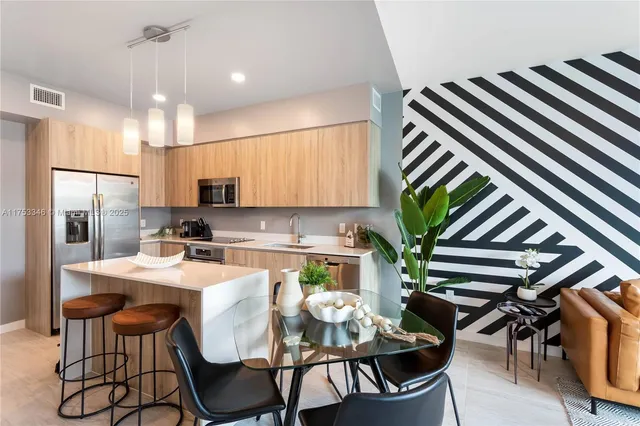 a kitchen with stainless steel appliances kitchen island granite countertop a dining table chairs and white cabinets