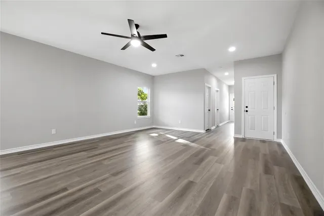 a view of empty room with wooden floor and ceiling fan