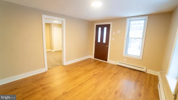 a view of an empty room with wooden floor and a window