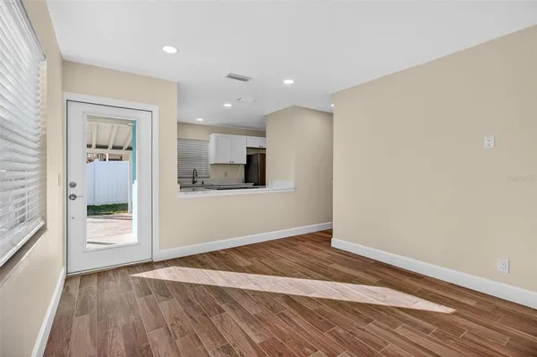 a view of an empty room with wooden floor and a window