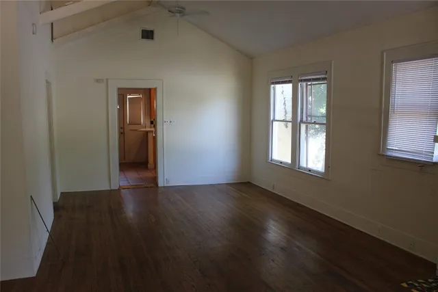 a view of an empty room with wooden floor and a window