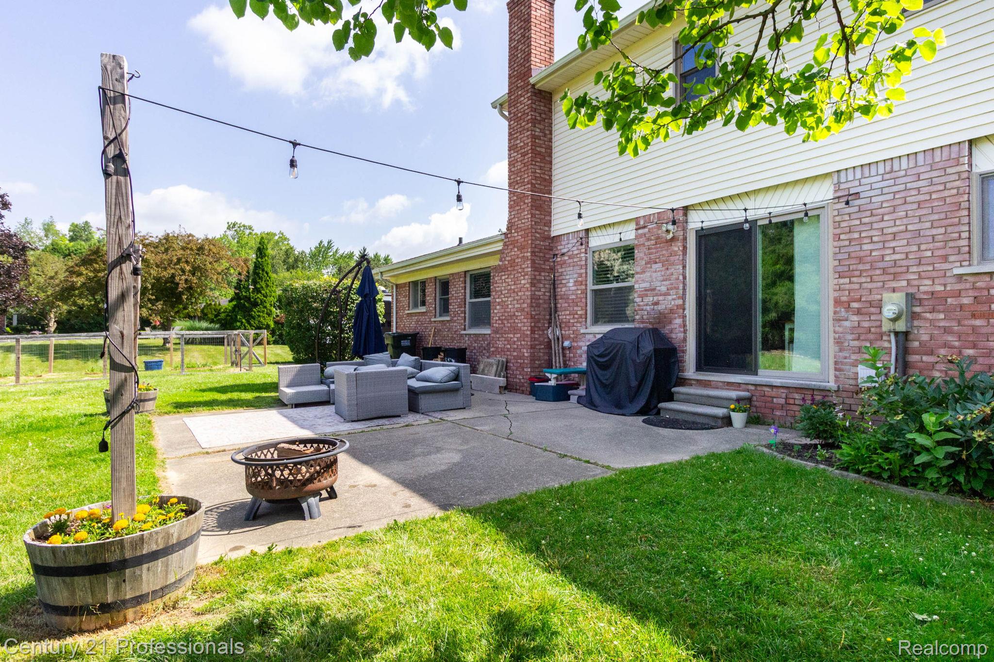 671 Bridgestone Drive Rochester, MI 48309 - Photo 47 of 50 Expansive concrete patio with string lighting, a fire pit, and direct access to the interior via a sliding glass door