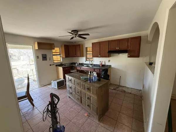 a kitchen with a refrigerator a stove top oven a sink a dining table and chairs