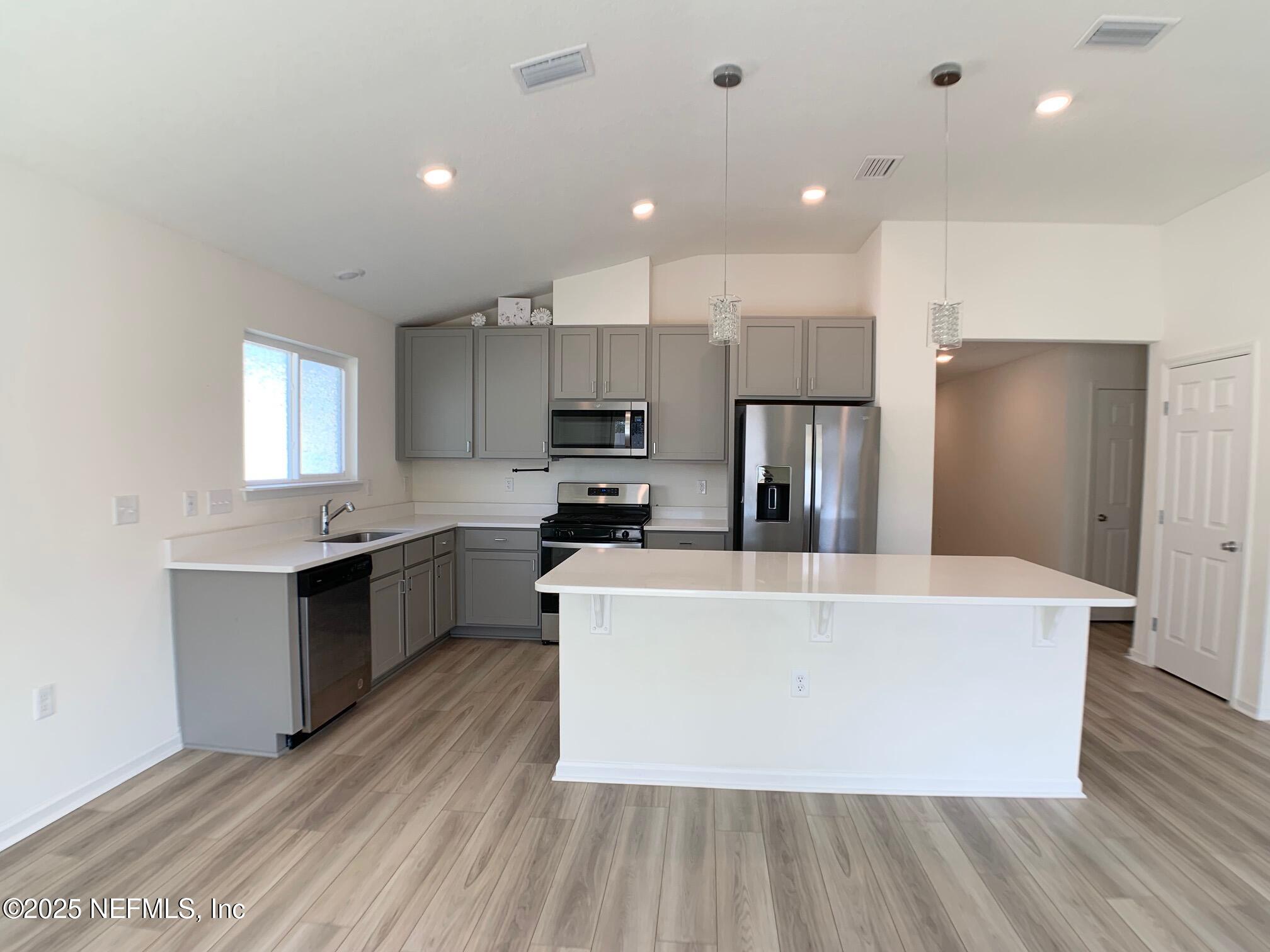 7948 Rippa Vly Way Jacksonville, FL 32222 - Photo 16 of 30 a large kitchen with stainless steel appliances granite countertop a large refrigerator a sink dishwasher and a oven with wooden floor