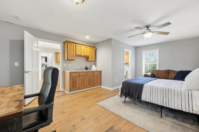 a bedroom with a bed chair and wooden floor