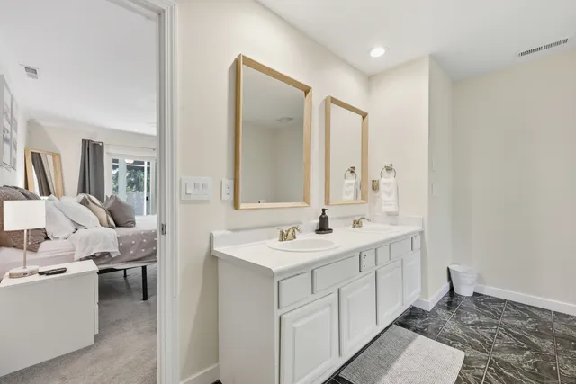 a spacious bathroom with a double vanity sink a mirror and next to a window