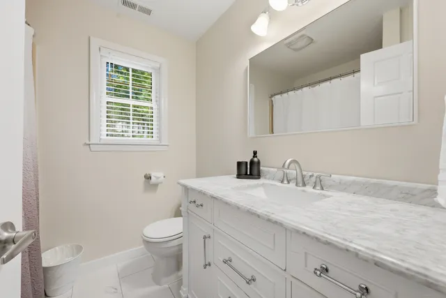 a bathroom with a granite countertop toilet a sink a mirror and a window