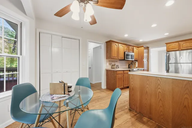 a kitchen with stainless steel appliances granite countertop a dining table chairs and a refrigerator