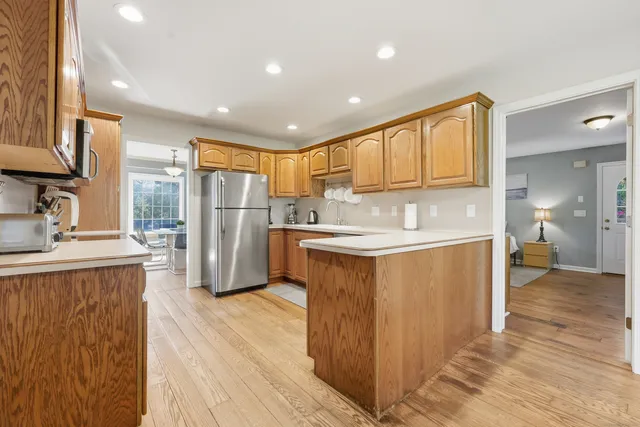 a kitchen with stainless steel appliances granite countertop a refrigerator a sink dishwasher a oven with white cabinets and wooden floor