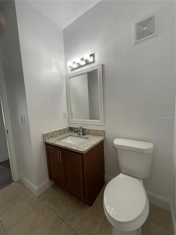 3739 Seneca Club Loop, Unit A Orlando, FL 32808 - Photo 19 of 31 a bathroom with a granite countertop toilet and a sink