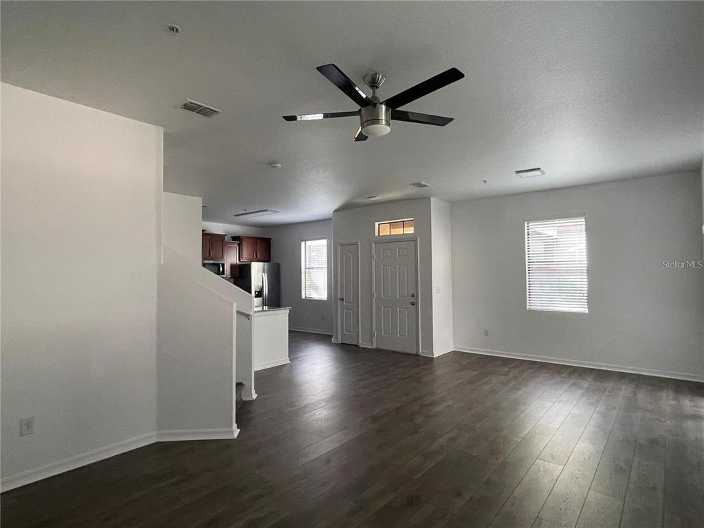 3739 Seneca Club Loop, Unit A Orlando, FL 32808 - Photo 3 of 31 an empty room with wooden floor a ceiling fan and windows