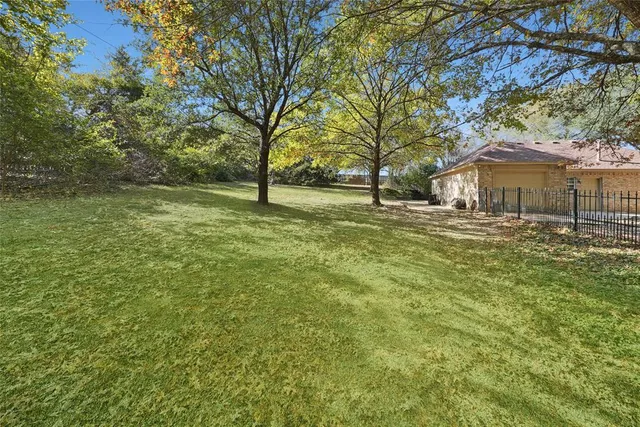 a backyard of a house with large trees and outdoor seating