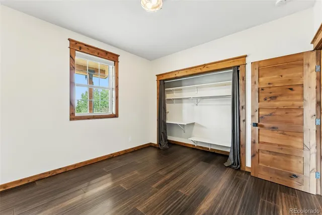 an empty room with wooden floor door and windows