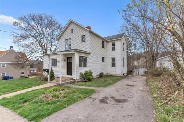 a view of a white house with a yard and large tree