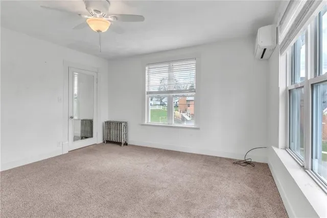 an empty room with windows and chandelier fan