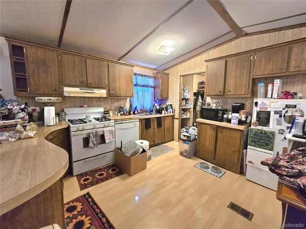 a kitchen with a refrigerator a stove a sink dishwasher and white cabinets with wooden floor