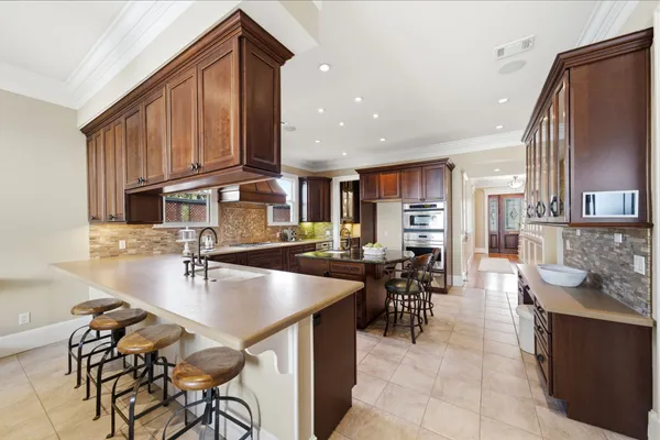 a kitchen with stainless steel appliances granite countertop a table chairs and a refrigerator