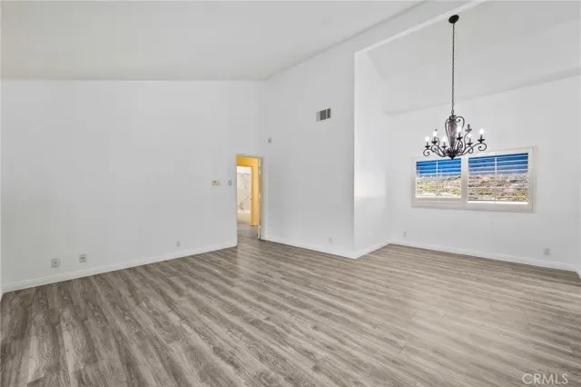 a view of a room with wooden floor chandeliers and kitchen view